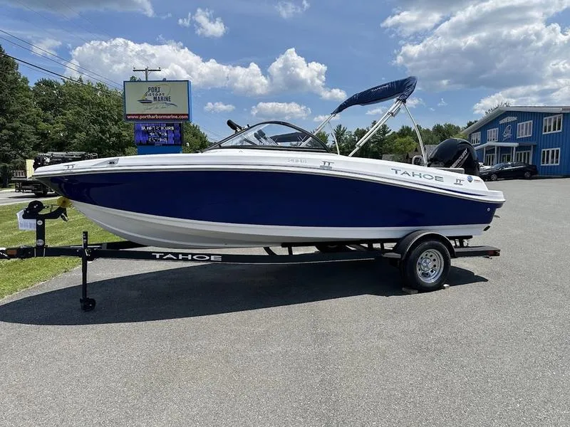 Slide: The Image of 2024 Tahoe 200 S boat on trailer, blue and white, parked outdoors. - 0