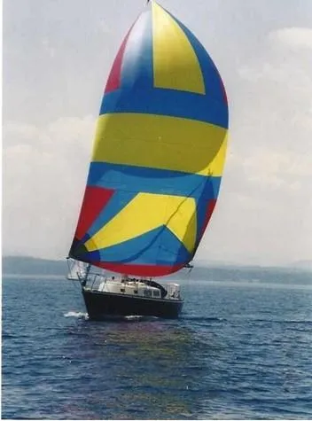 Slide: The Image of 1974 Tartan 30 sailboat with colorful spinnaker on open water. - 0