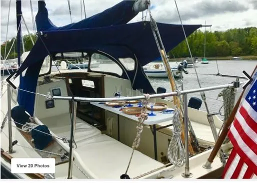 Slide: The Image of 1974 Tartan 30 sailboat with American flag, docked on a calm lake. - 11