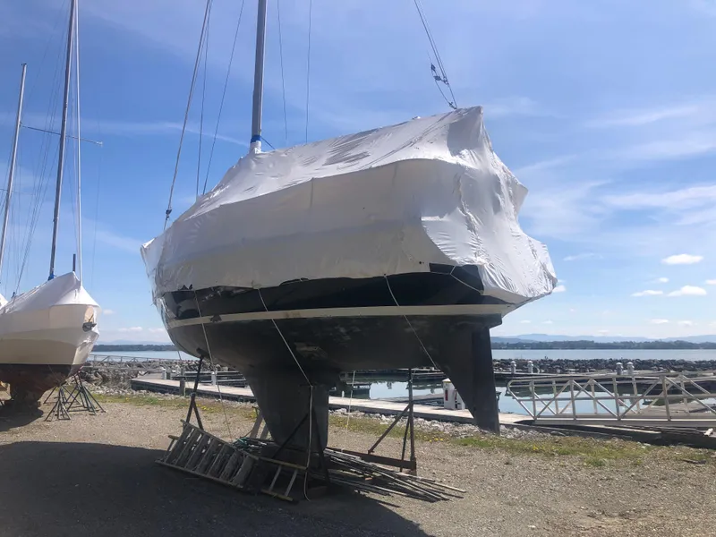 Slide: The Image of 1974 Tartan 30 sailboat covered in tarp, docked near a marina under a clear blue sky. - 17