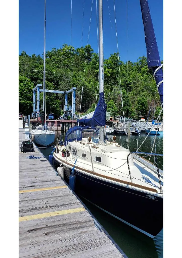 Slide: The Image of 1974 Tartan 30 sailboat docked at a marina, surrounded by lush greenery. - 4
