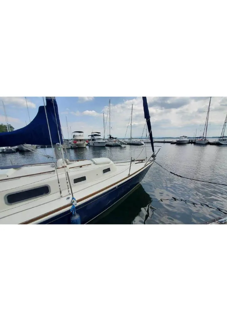 Slide: The Image of 1974 Tartan 30 sailboat docked in a marina with other boats under a cloudy sky. - 5
