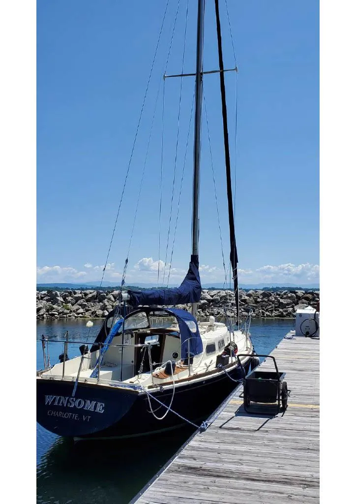 Slide: The Image of 1974 Tartan 30 sailboat docked at a marina under a clear blue sky. - 6