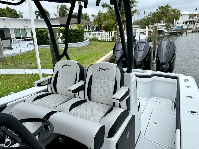 Slide: The Image of 2024 Yellowfin 36 boat with dual seats and triple outboard engines docked by a canal. - 13