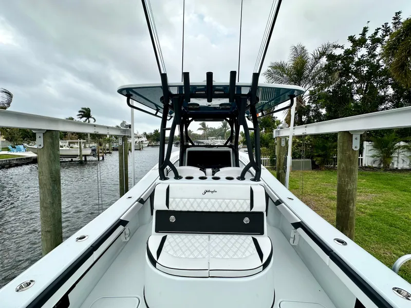 Slide: The Image of 2024 Yellowfin 36 boat docked by a canal, featuring a sleek white and black design. - 14
