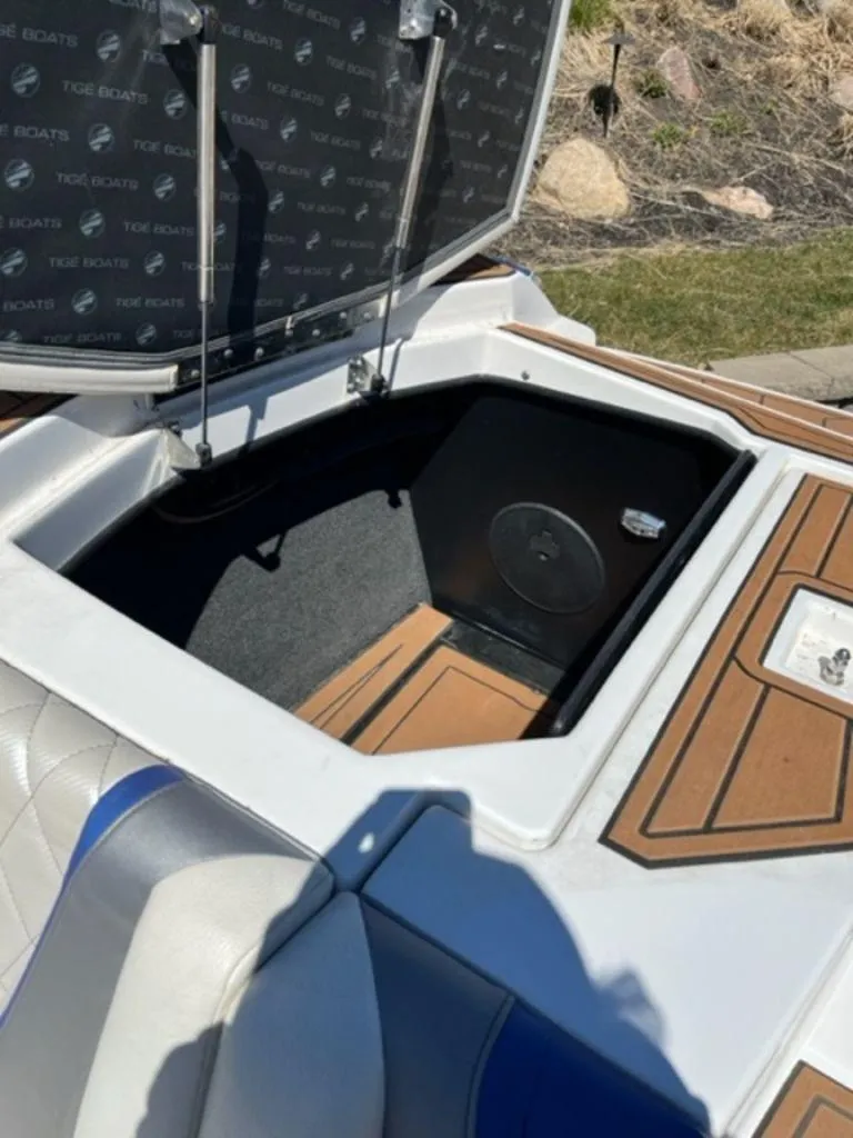Slide: The Image of Open storage compartment on a 2016 Tigé RZX boat with cushioned seating. - 7