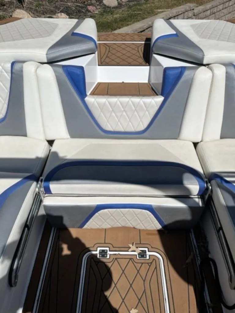 Slide: The Image of 2016 Tigé RZX boat interior with white, gray, and blue cushioned seating. - 9