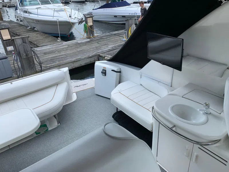 Slide: The Image of 1997 Sea Ray 370 Sundancer interior with seating, sink, and TV at marina. - 13