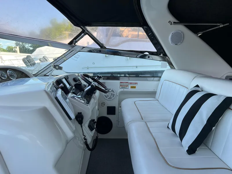 Slide: The Image of 1997 Sea Ray 370 Sundancer cockpit with white seating and striped pillow. - 28