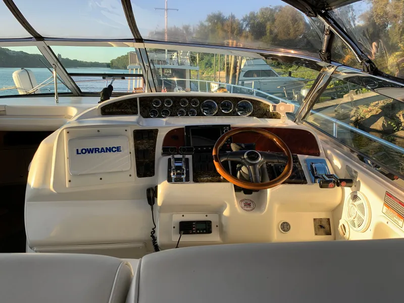 Slide: The Image of 1997 Sea Ray 370 Sundancer helm with Lowrance navigation system, docked by a scenic waterway. - 31