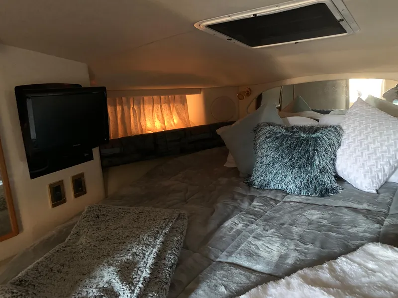 Slide: The Image of Cozy cabin interior of a 1997 Sea Ray 370 Sundancer with plush bedding and a mounted TV. - 46
