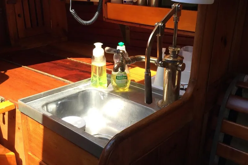 Slide: The Image of 1955 Concordia Yawl kitchen sink with soap dispensers and wooden cabinetry. - 10