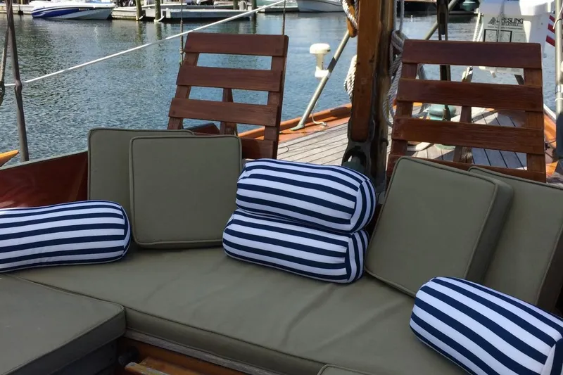 Slide: The Image of Cozy seating on 1955 Concordia Yawl with striped cushions, docked at marina. - 16