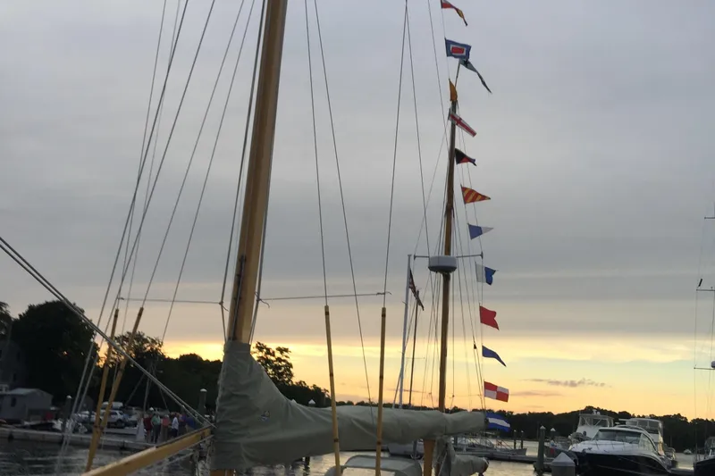 Slide: The Image of Sailboat Concordia Yawl (Hull #33) from 1955 with colorful flags at sunset. - 19