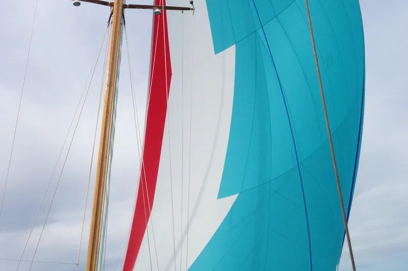 Slide: The Image of Colorful sails of a 1955 Concordia Yawl (Hull #33) against a cloudy sky. - 23