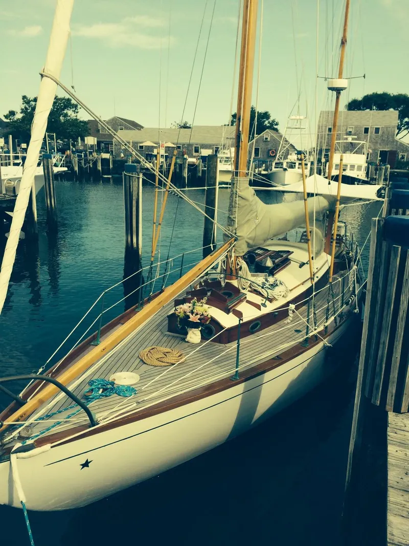 Slide: The Image of 1955 Concordia Yawl (Hull #33) docked at a marina, showcasing classic wooden design. - 27