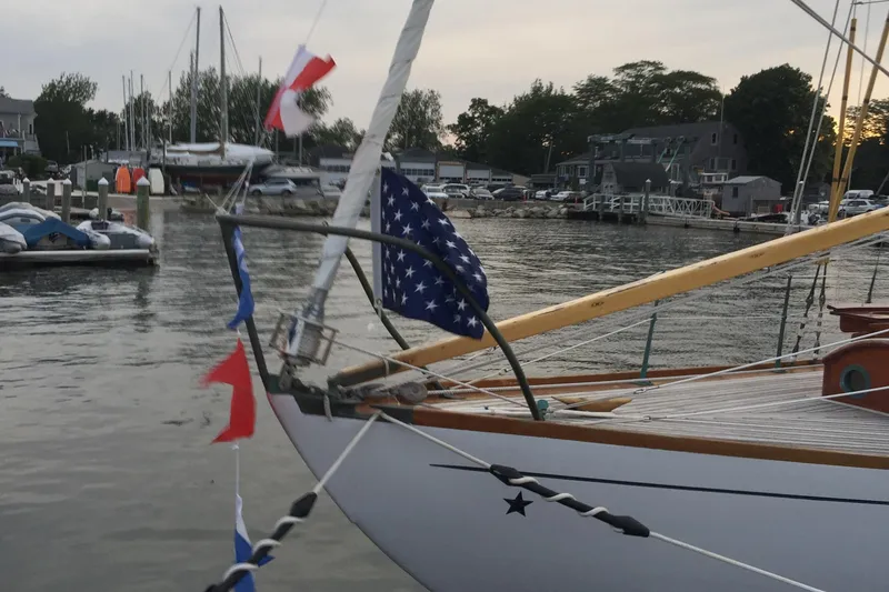 Slide: The Image of 1955 Concordia Yawl (Hull #33) docked with nautical flags, serene marina backdrop. - 31