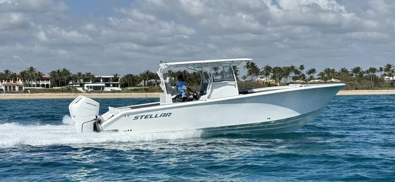 Slide: The Image of 2024 Custom 335 boat cruising on blue water near a sandy beach. - 0