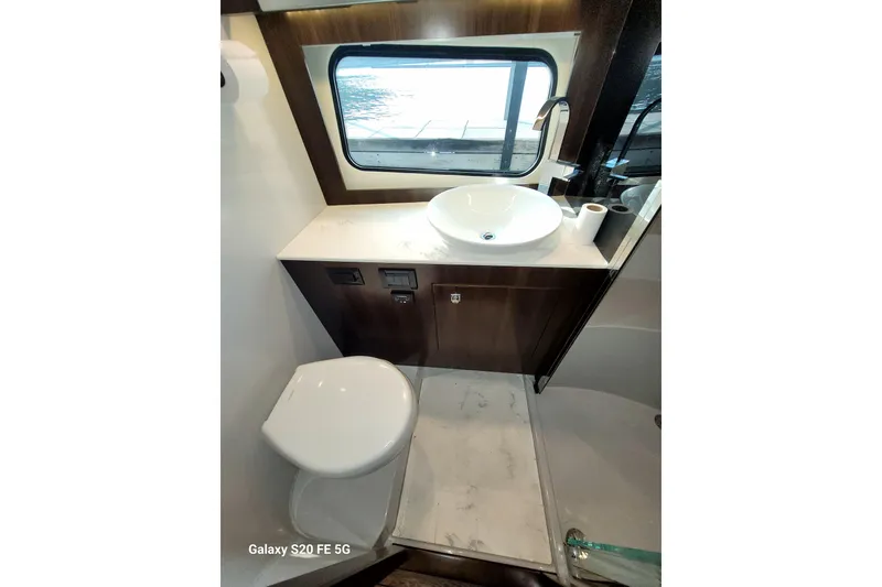 Slide: The Image of 2021 Cruisers Yachts 39 Express Coupe bathroom with sink, toilet, and window view. - 66