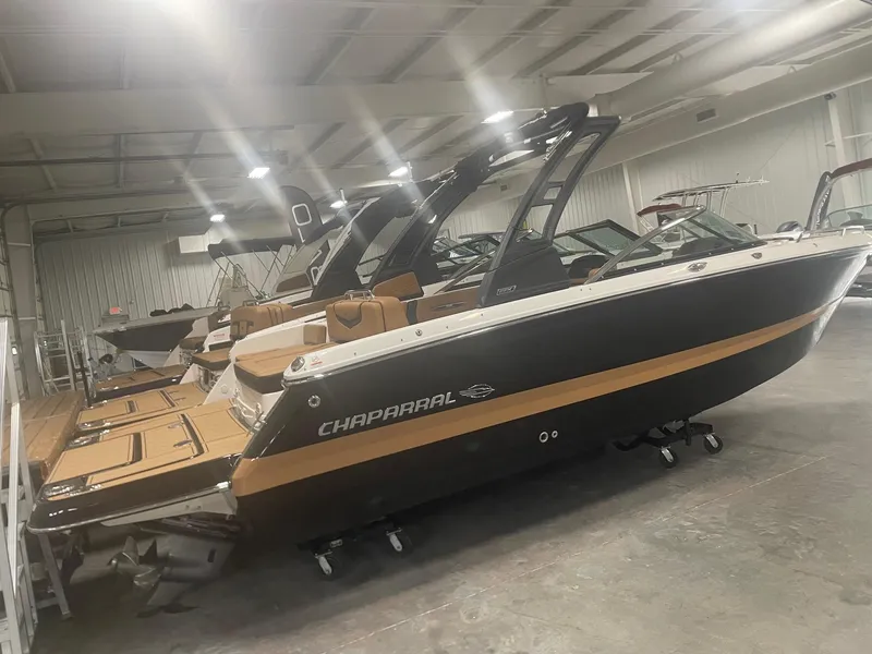 Slide: The Image of 2024 Chaparral 247 SSX boat in showroom, black and tan color scheme. - 2