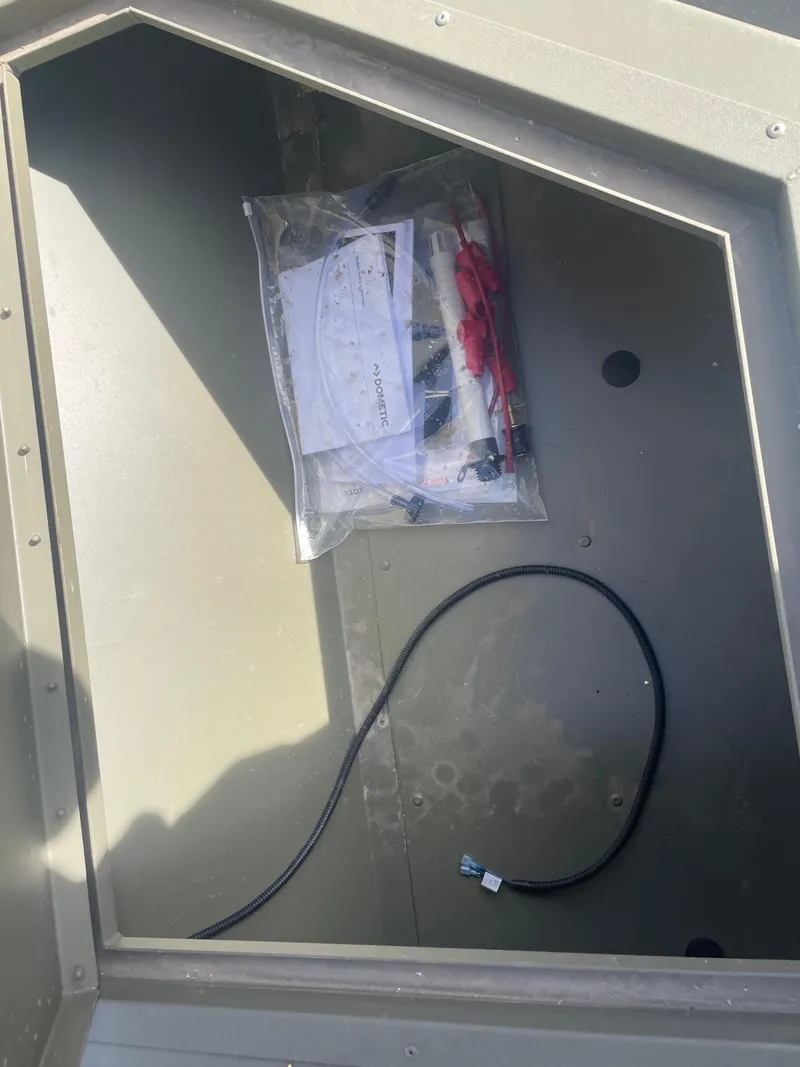 Slide: The Image of Storage compartment of 2024 Tracker Grizzly 2072 CC Sportsman boat with wiring and accessories. - 16