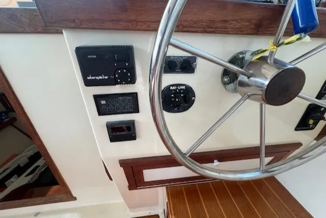 Slide: The Image of 1989 Blue Seas Flybridge Cruiser helm with steering wheel and control panel. - 11