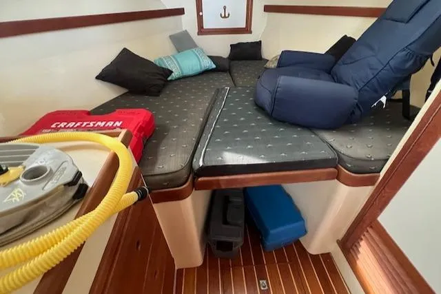 Slide: The Image of 1989 Blue Seas Flybridge Cruiser cabin with cushions, life jacket, and wooden flooring. - 22