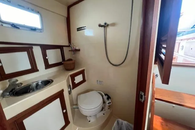Slide: The Image of 1989 Blue Seas Flybridge Cruiser bathroom with shower, sink, and toilet, featuring wood accents. - 26