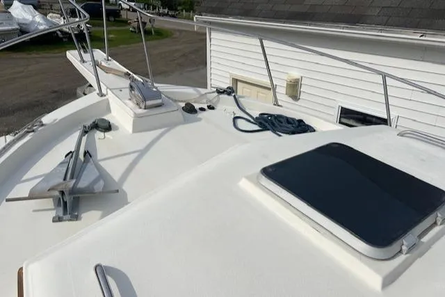 Slide: The Image of 1989 Blue Seas Flybridge Cruiser deck with anchor and hatch, docked near a white building. - 35
