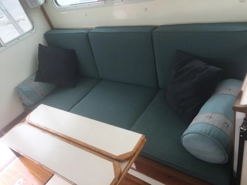Slide: The Image of Interior of 1989 Blue Seas Flybridge Cruiser with teal seating and wooden table. - 4