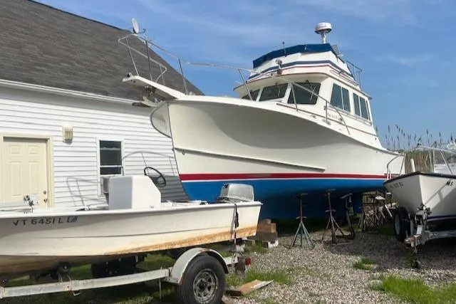 Slide: The Image of 1989 Blue Seas Flybridge Cruiser docked beside a house, showcasing its sleek design. - 47