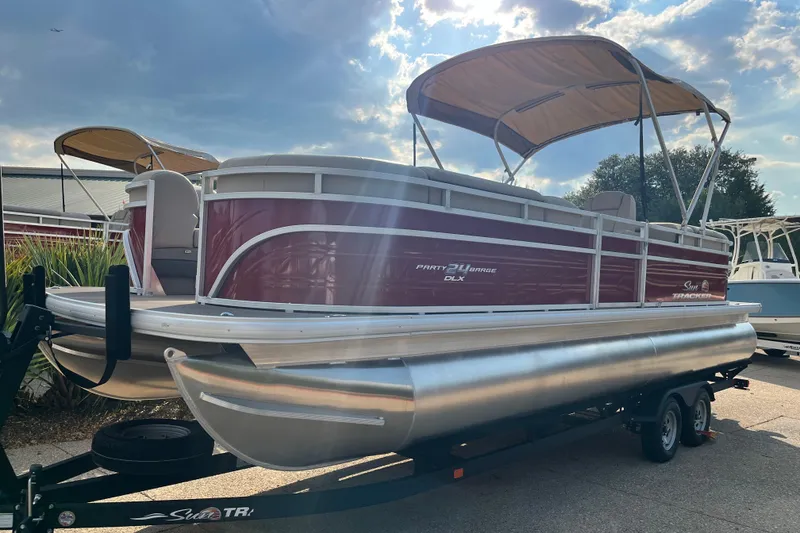 The Image of 2024 Sun Tracker Party Barge 24 DLX pontoon boat on trailer, under a sunny sky. - 0
