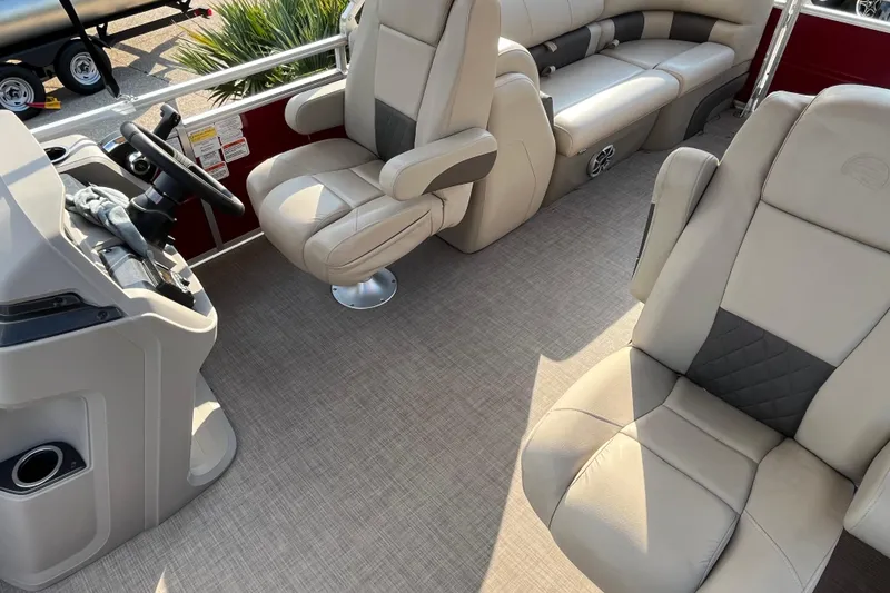 Slide: The Image of 2024 Sun Tracker Party Barge 24 DLX interior with plush seating and steering console. - 6