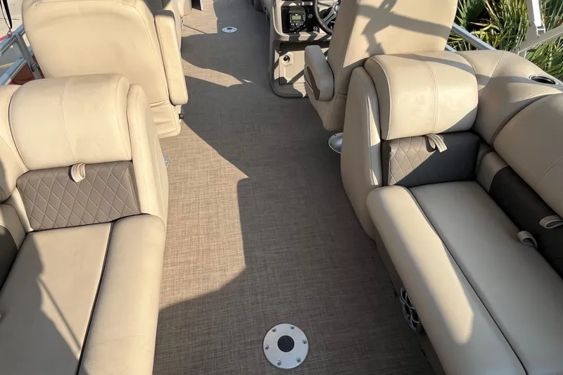 Slide: The Image of 2024 Sun Tracker Party Barge 24 DLX interior with beige seating and steering console. - 8