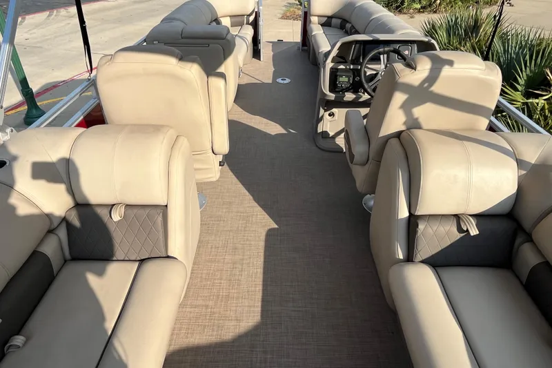 Slide: The Image of 2024 Sun Tracker Party Barge 24 DLX interior with beige seating and steering console. - 9
