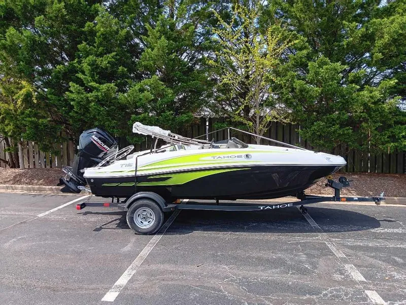 Slide: The Image of 2024 Tahoe T16 boat on trailer in parking lot, surrounded by trees. - 0