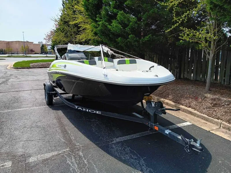 Slide: The Image of 2024 Tahoe T16 boat on trailer in parking lot, surrounded by trees. - 2