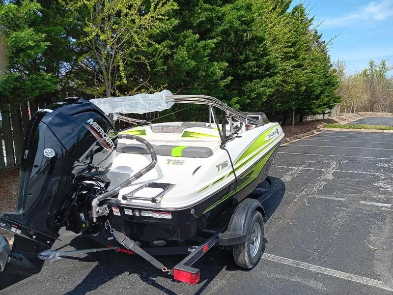 Slide: The Image of 2024 Tahoe T16 boat with Mercury engine on trailer, parked near trees. - 6
