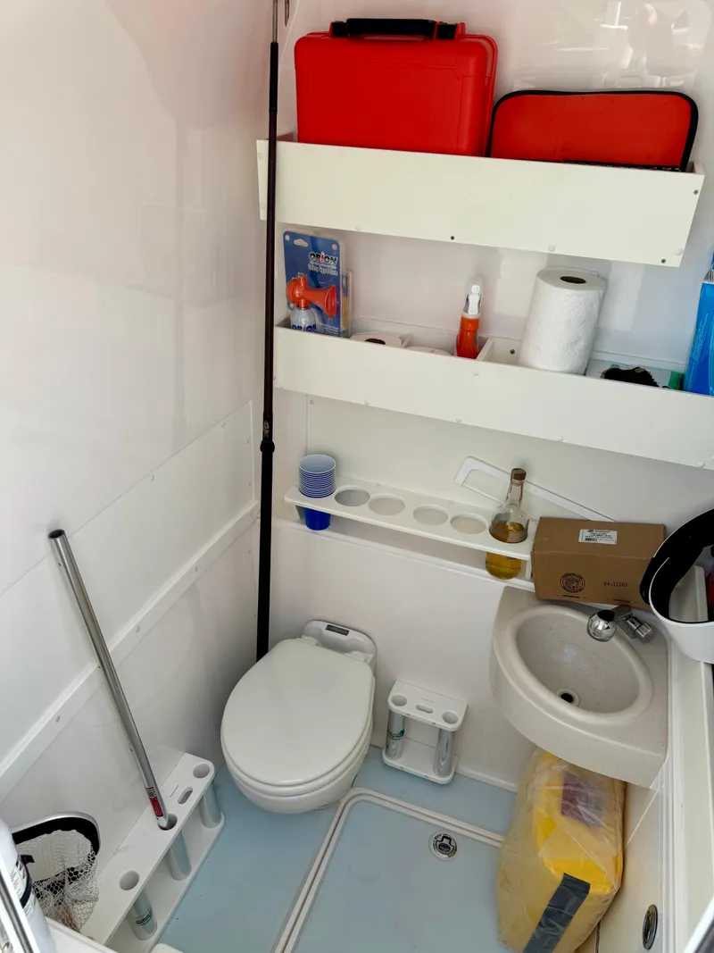 Slide: The Image of 2020 Invincible 36' Open Fisherman boat bathroom with toilet, sink, and storage shelves. - 8