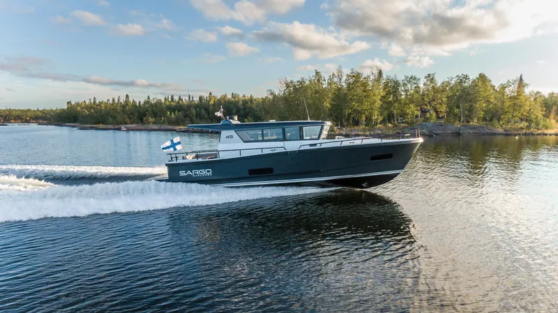 Slide: The Image of 2027 Sargo 45 Cat A or B motorboat cruising on a scenic lake. - 2