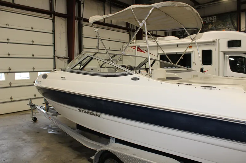 Slide: The Image of 2013 Stingray 208 CK boat with canopy in indoor storage. - 16