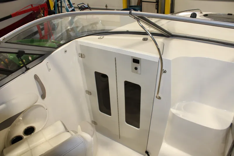 Slide: The Image of 2013 Stingray 208 CK boat interior with white seating and storage compartments. - 26
