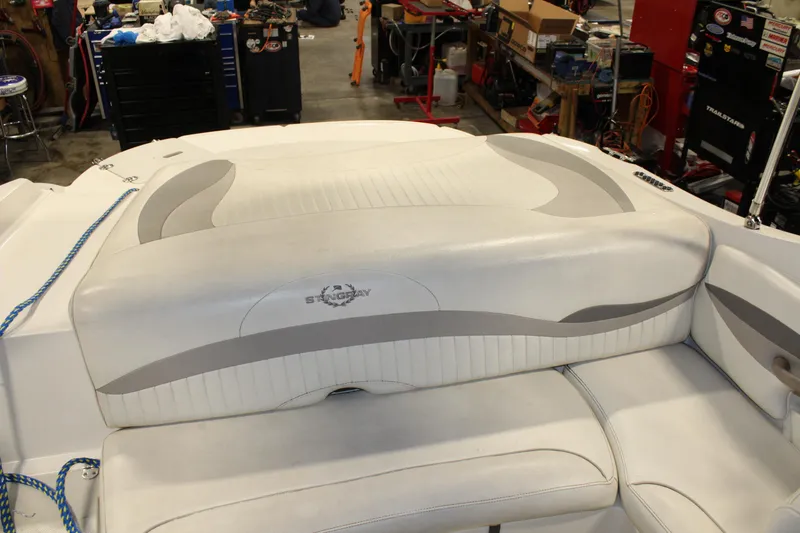 Slide: The Image of 2013 Stingray 208 CK boat interior with white and gray seating in a workshop. - 29