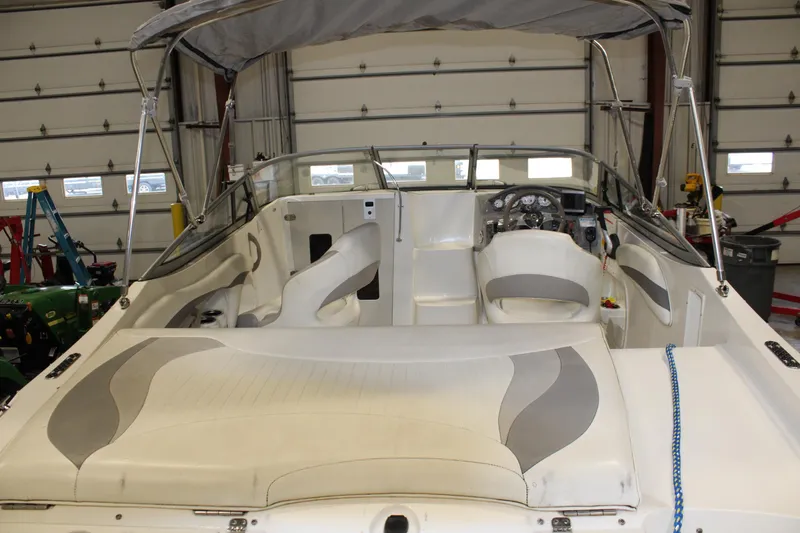 Slide: The Image of 2013 Stingray 208 CK boat interior with white and gray seating in a garage. - 5