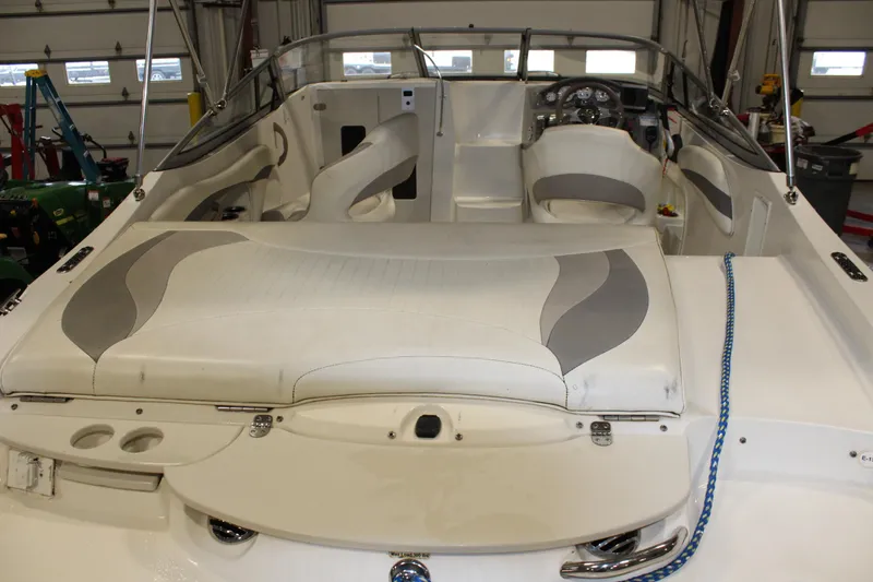 Slide: The Image of 2013 Stingray 208 CK boat interior with white and gray seating in a garage. - 7