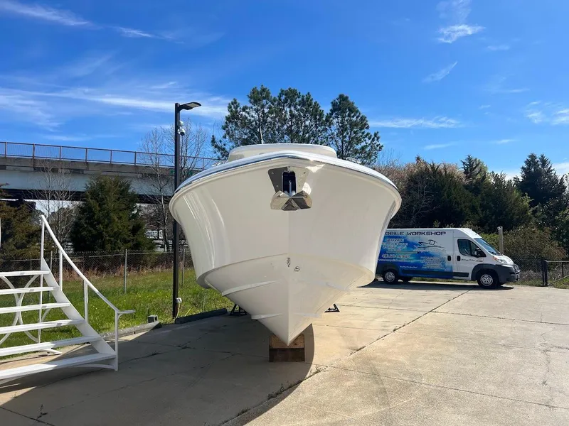 Slide: The Image of 2024 Everglades 315 Center Console boat on a concrete lot with a blue sky background. - 2