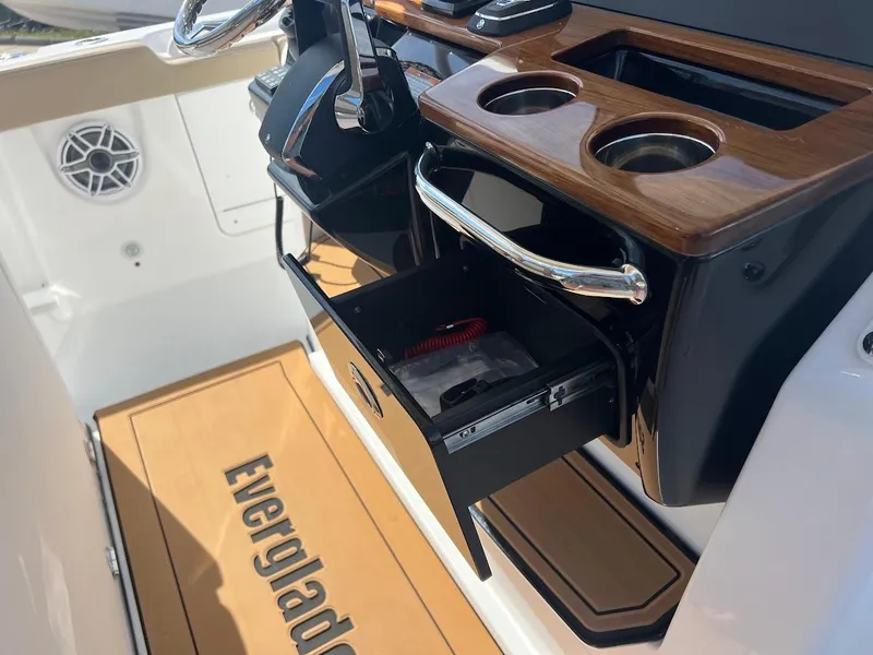 Slide: The Image of 2024 Everglades 315 Center Console boat interior with open storage drawer and cup holders. - 25
