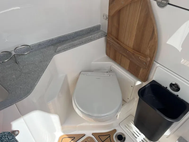Slide: The Image of 2024 Everglades 315 Center Console boat interior bathroom with toilet and wooden door. - 37