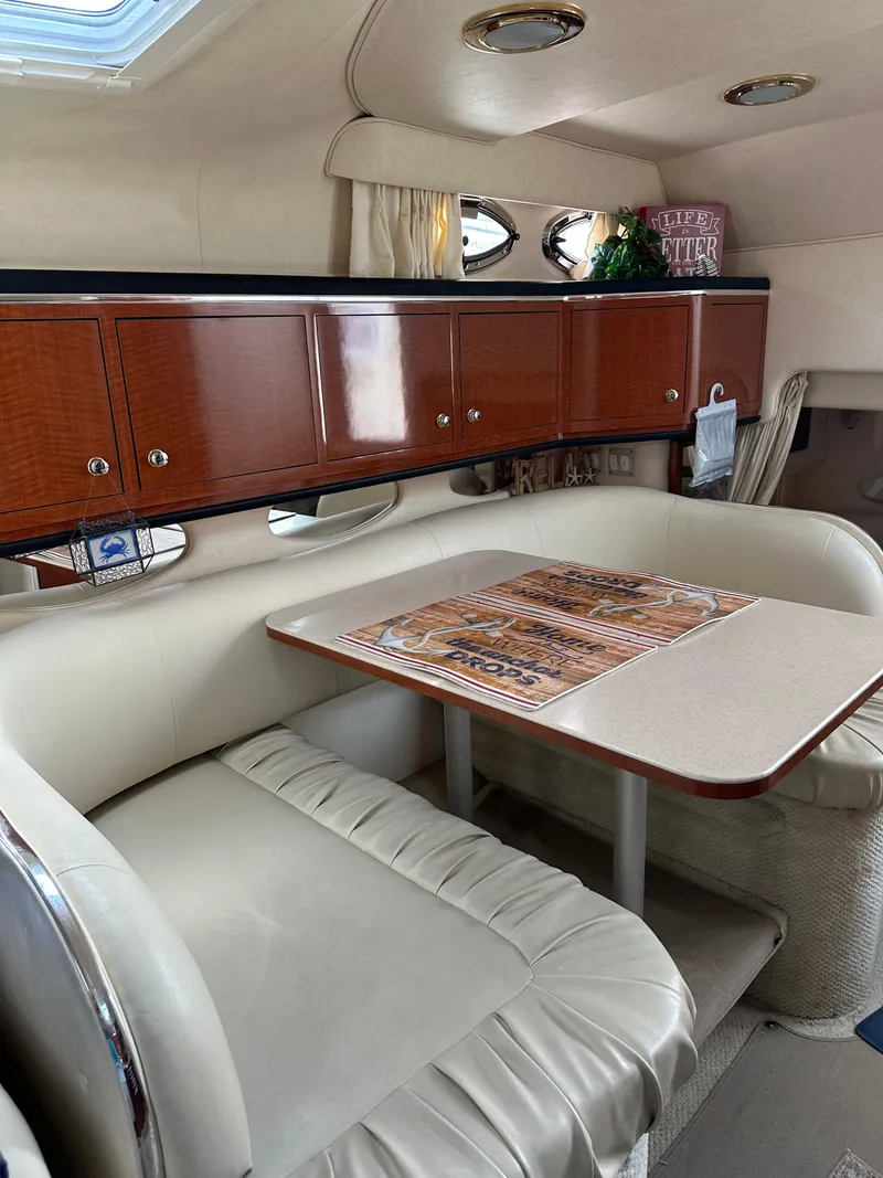 Slide: The Image of 2002 Sea Ray 310 Sundancer cabin interior with dining area and wooden cabinets. - 14