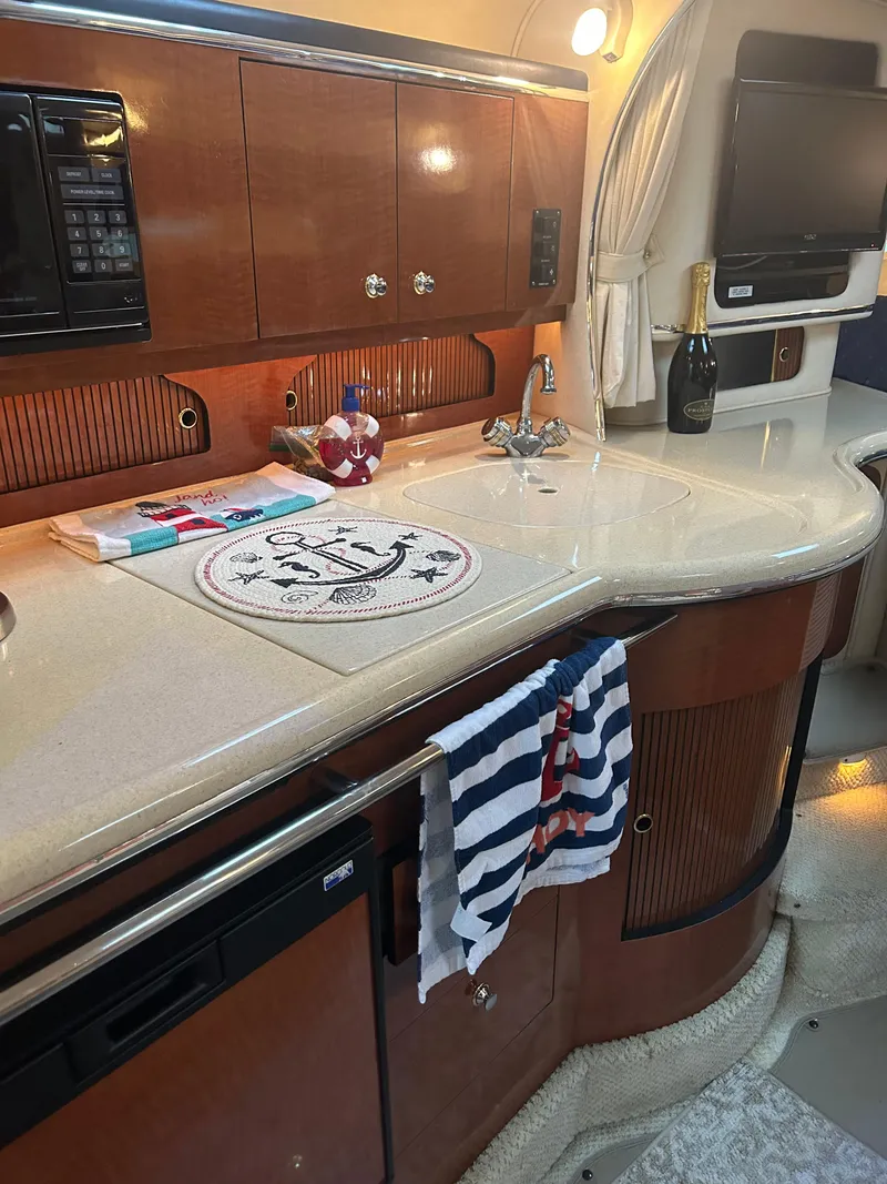 Slide: The Image of 2002 Sea Ray 310 Sundancer galley with wooden cabinetry, countertop, and nautical decor. - 16
